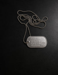 Metal dog tag with engraved text on a black background